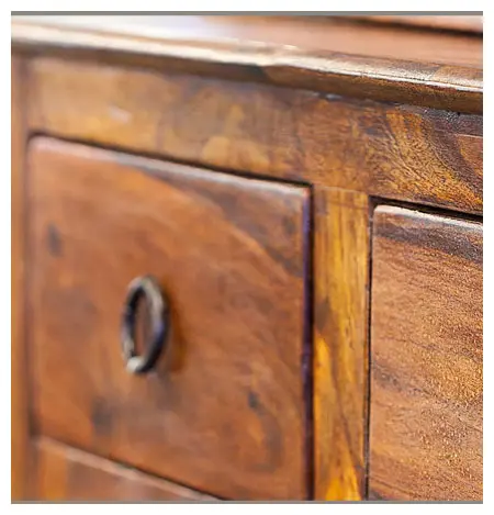 Close-up of an antique wooden drawer with a metal handle, highlighting the wood's texture and natural grain.